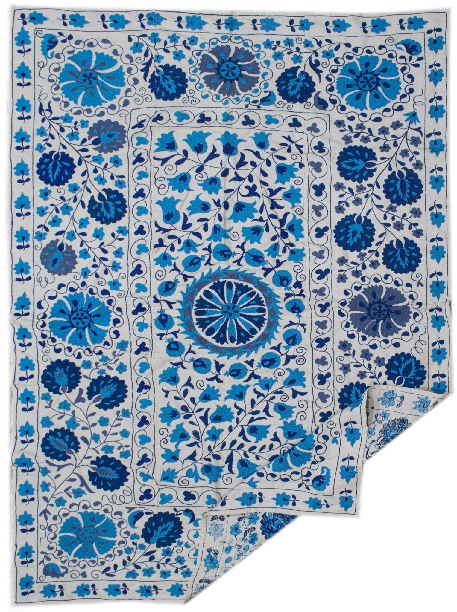 Handmade Uzbek suzani featuring blue floral embroidery on a white cotton base.