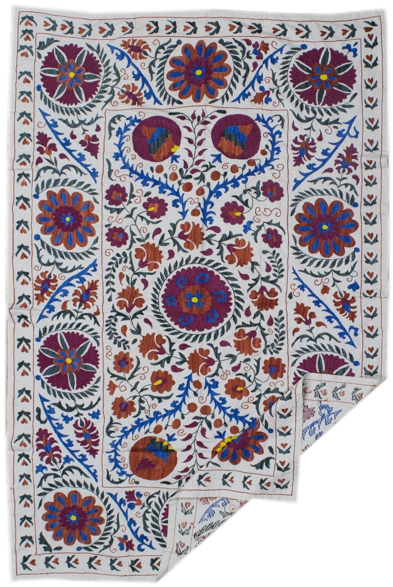Handmade Uzbek suzani textile featuring colorful floral and botanical embroidery on a cotton base.