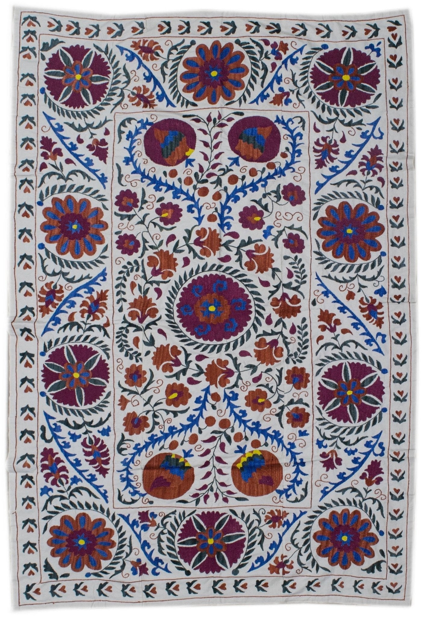 Handmade Uzbek suzani featuring intricate floral and fruit embroidery on a white cotton base.