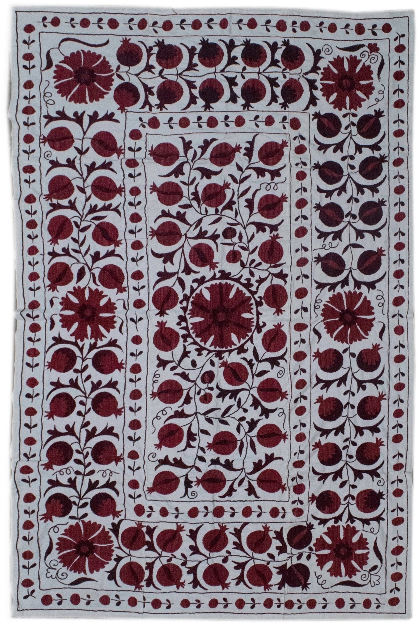 Hand-embroidered Uzbek suzani featuring a traditional pomegranate and floral motif in deep red.