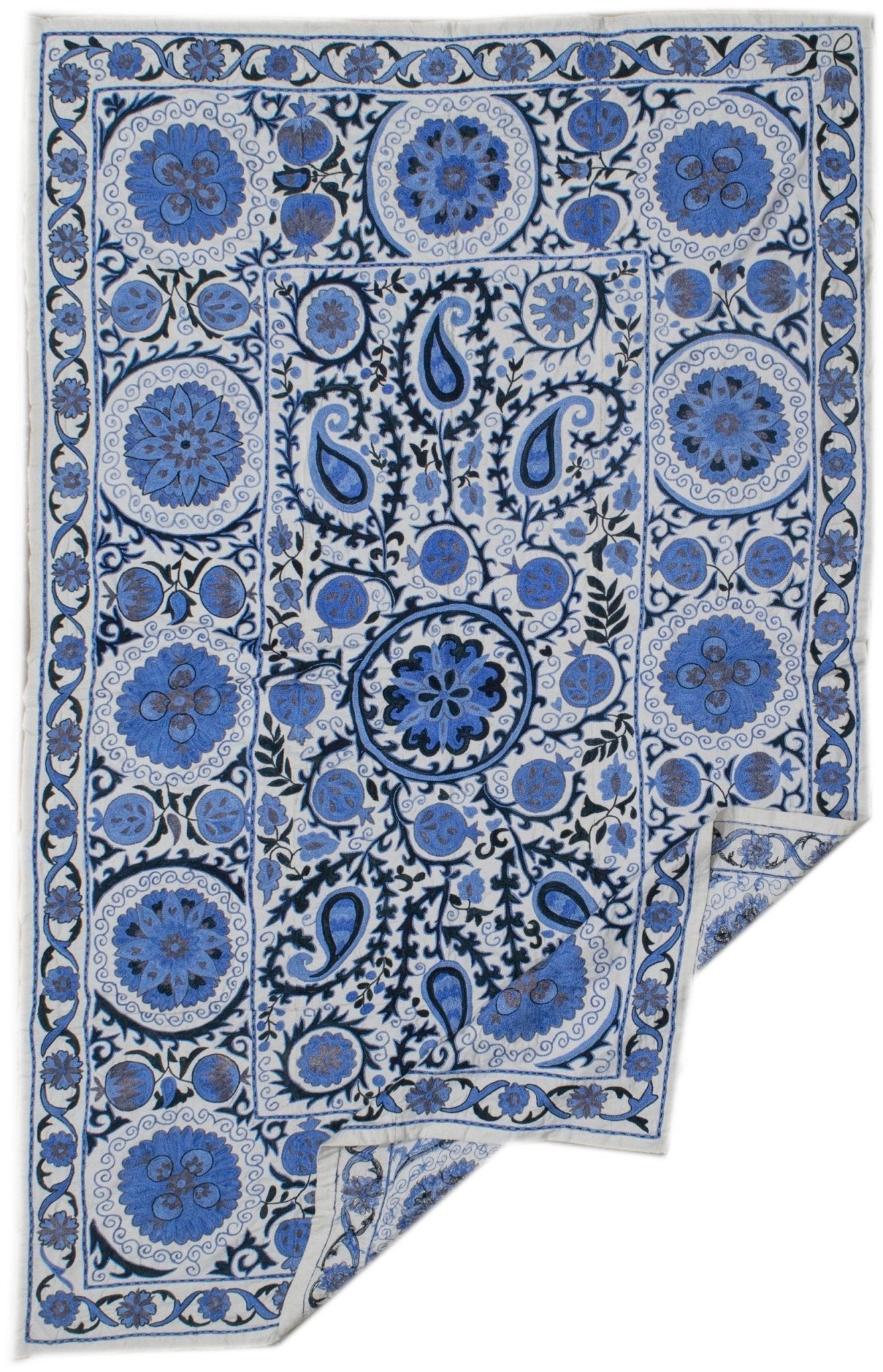 Handmade Uzbek suzani featuring blue floral and paisley embroidery on a white cotton base.