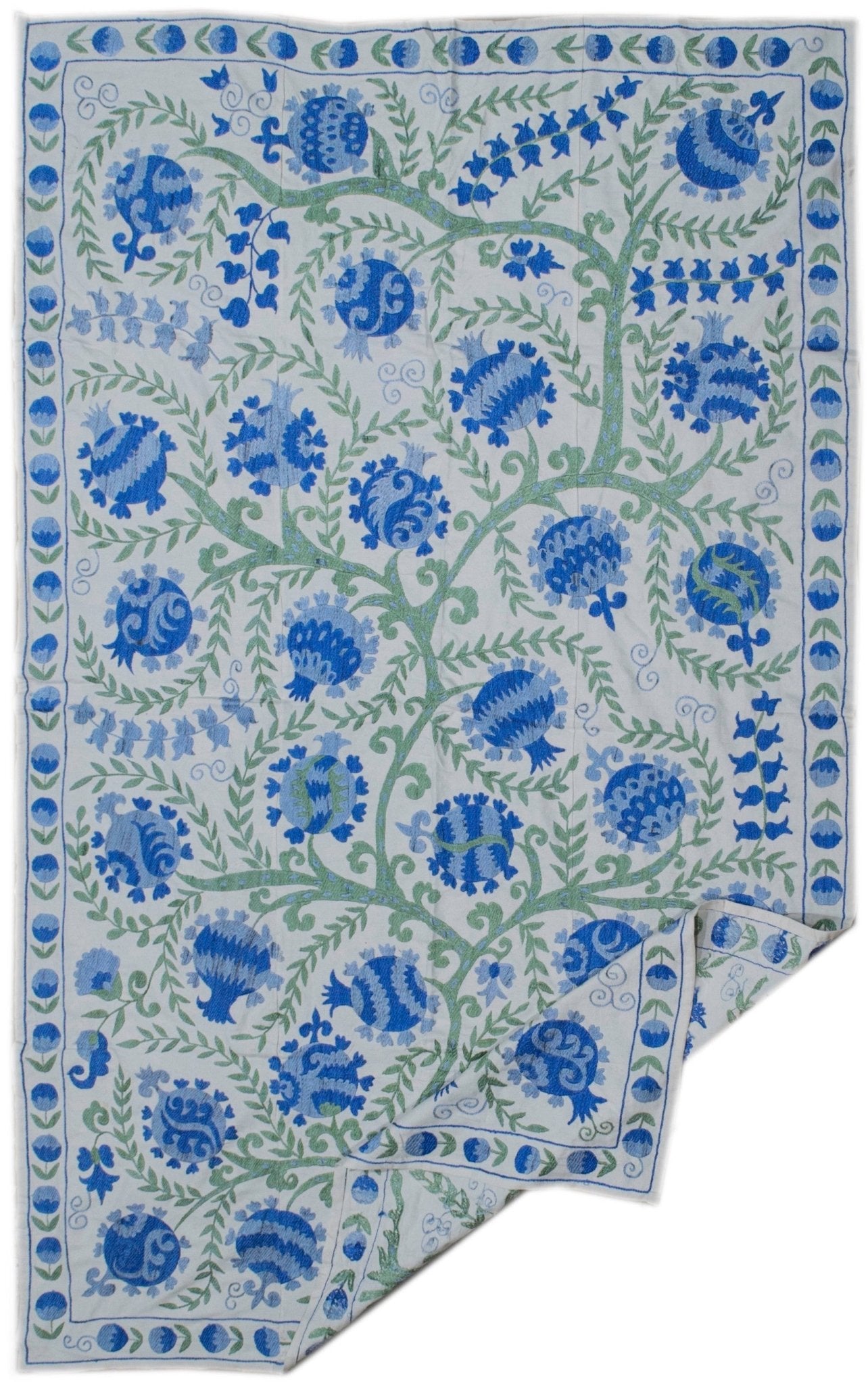 Handmade Uzbek suzani featuring blue pomegranate and floral embroidery on a white cotton base.