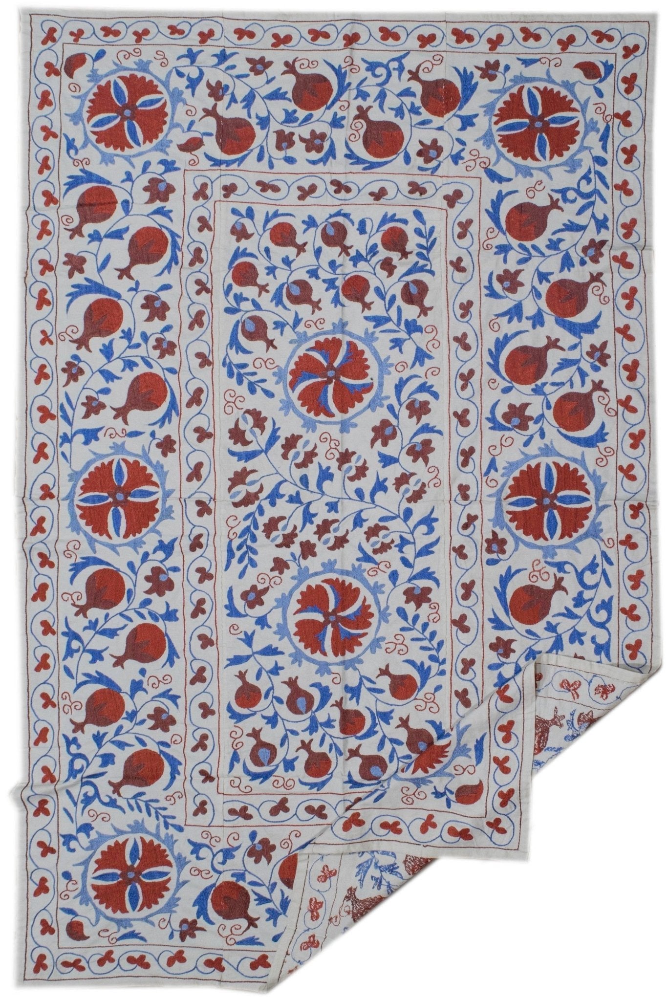 Handmade Uzbek suzani featuring red floral and pomegranate embroidery on a white cotton base.