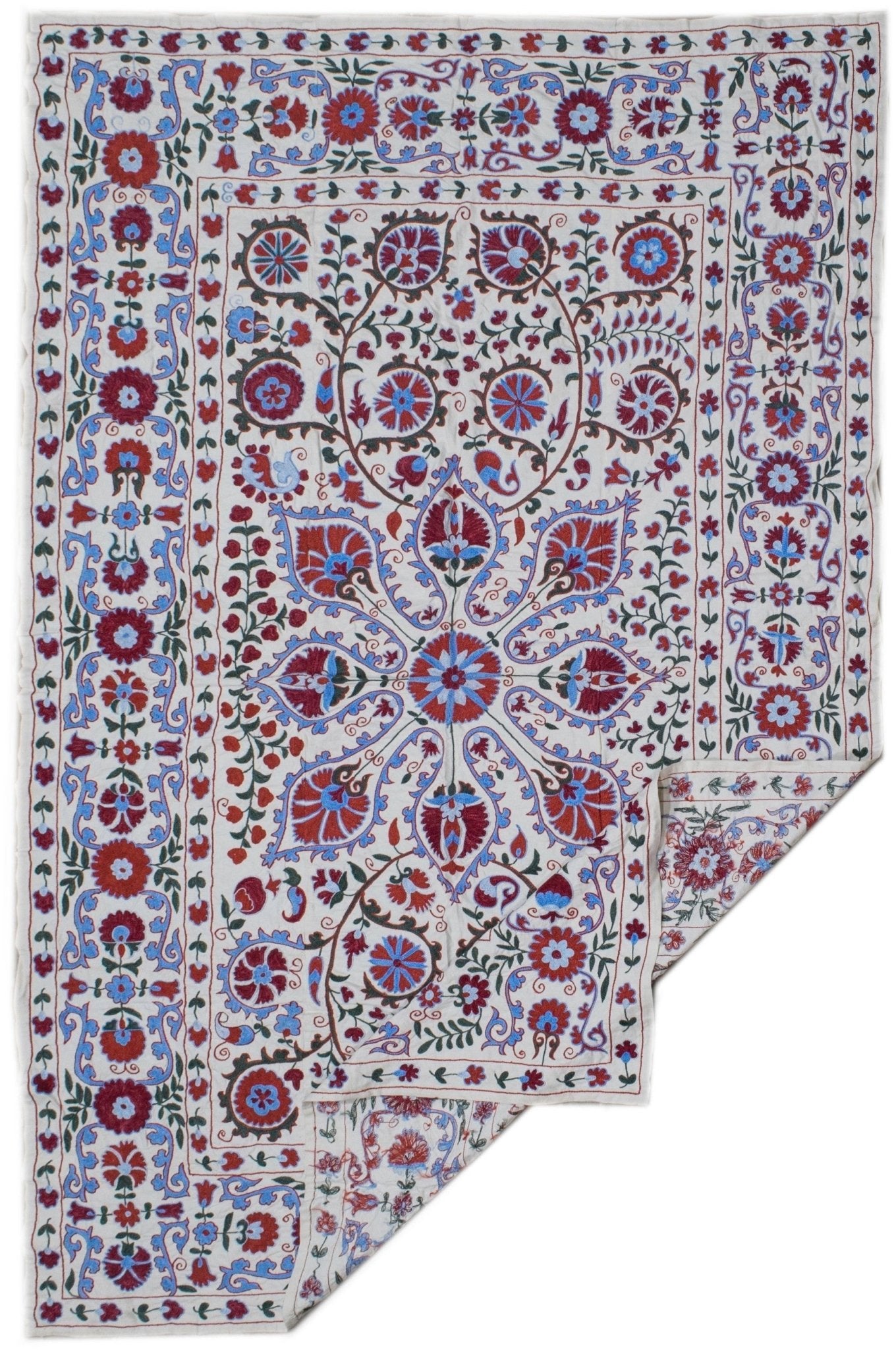 A hand-embroidered Uzbek suzani featuring intricate floral and vine motifs in red and blue silk.
