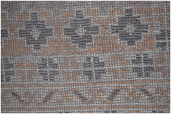 A close-up of a vintage Afghan Baluch rug featuring geometric patterns in brown and orange wool.