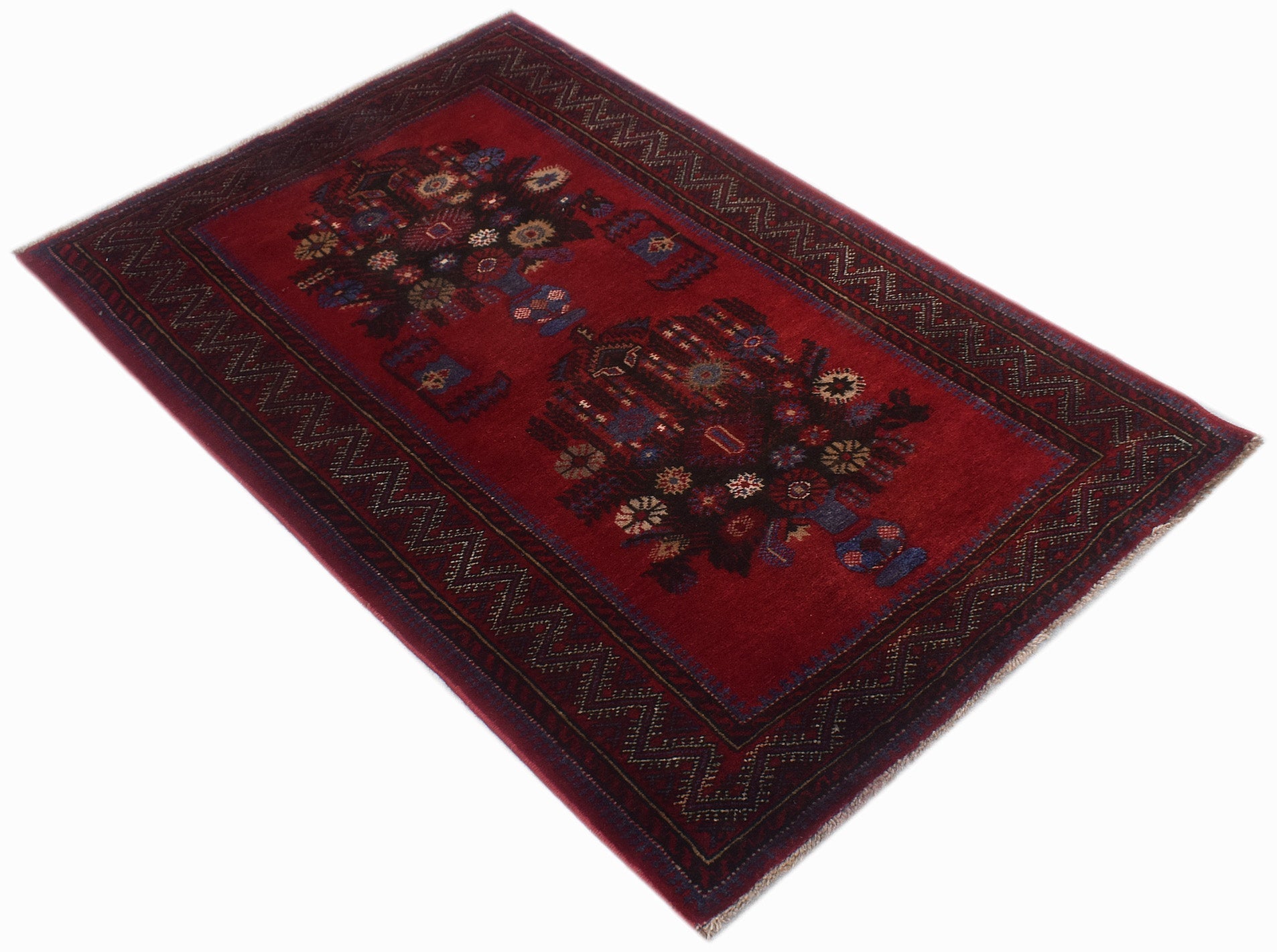 A vintage handwoven Afghan Baluch rug featuring a deep red field with two floral medallion motifs.