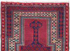 A vintage handmade Afghan Baluch rug featuring a geometric prayer design in red, blue, and ivory.