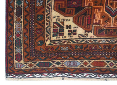 A corner view of a handmade vintage Afghan Baluch rug featuring geometric patterns in rust, cream, and blue.