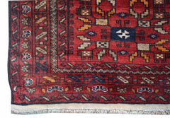 A handwoven vintage Afghan Baluch rug featuring geometric patterns in red, blue, and tan wool.