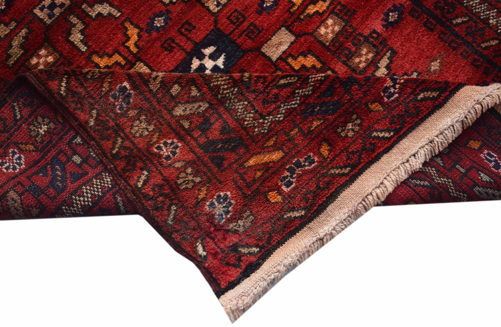 A handwoven vintage Afghan Baluch rug featuring a geometric red pattern and fringed edges.