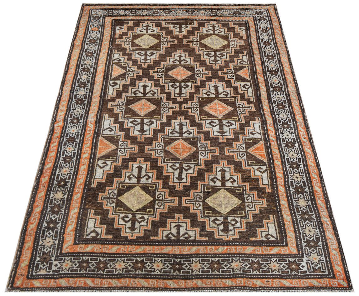 A vintage handwoven Afghan Baluch rug featuring a geometric diamond pattern in brown and orange.
