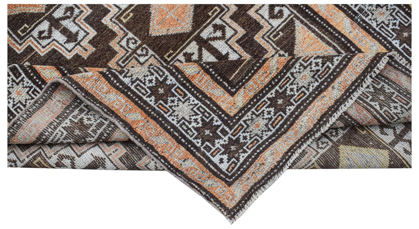 A handwoven vintage Afghan Baluch rug featuring geometric patterns in brown, orange, and cream.