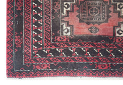 A vintage handmade Afghan Baluch rug featuring geometric patterns in red and black wool.