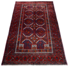 A vintage handmade Afghan Baluch rug featuring geometric patterns in deep red and blue tones.