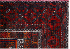 A close-up of a vintage Afghan Baluch rug featuring traditional geometric patterns in red and black.