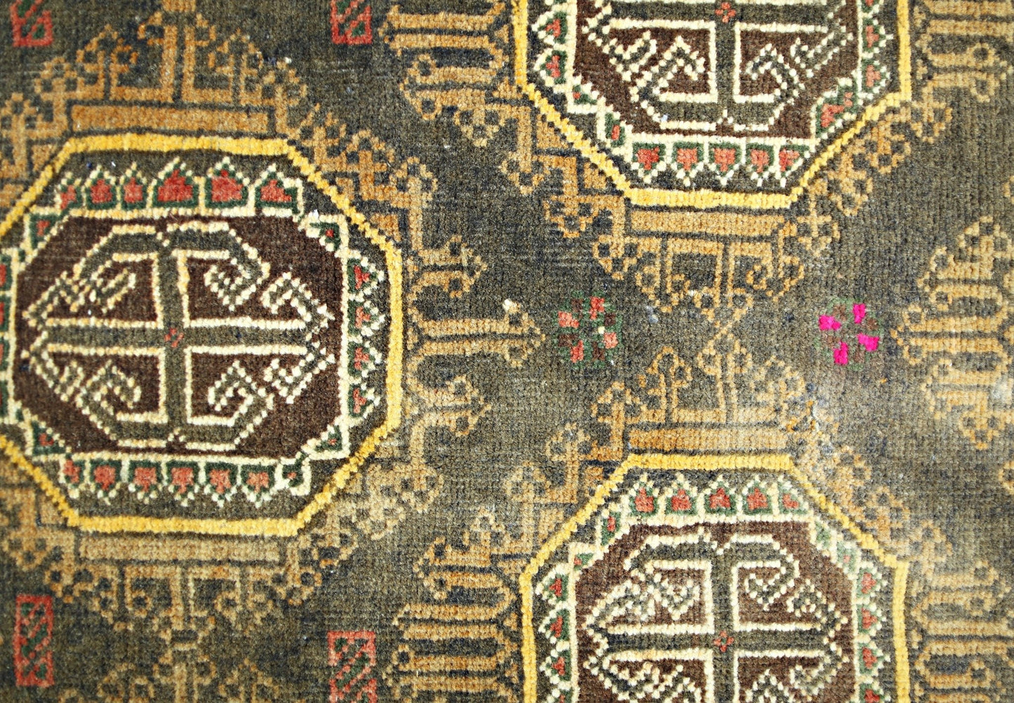 A vintage Afghan Baluch rug featuring geometric octagonal motifs in brown, red, and yellow wool.
