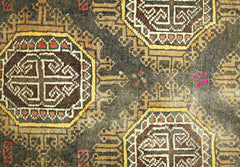 A vintage Afghan Baluch rug featuring geometric octagonal motifs in brown, red, and yellow wool.