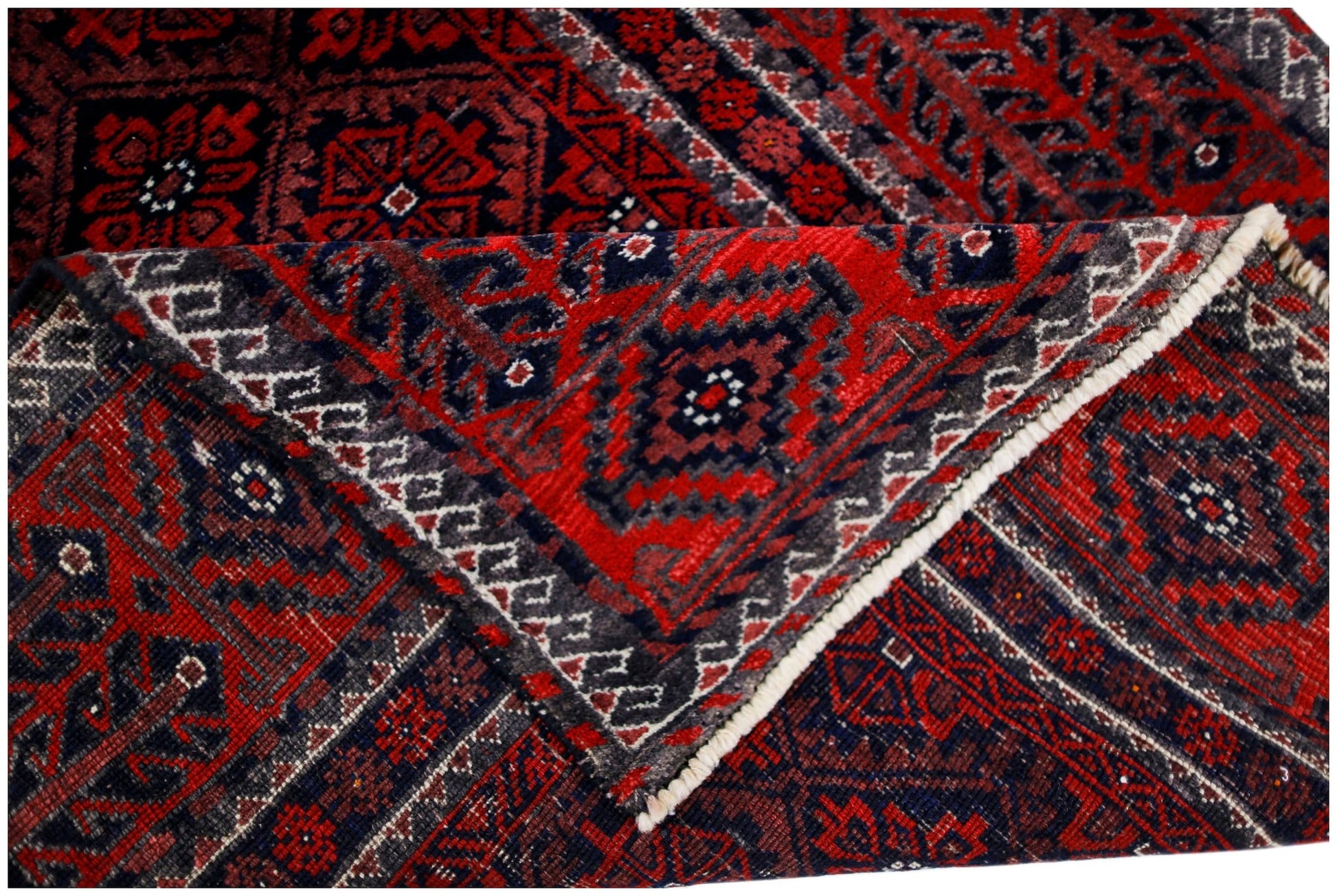 A handmade vintage Afghan Baluch rug featuring a geometric red and dark blue pattern.