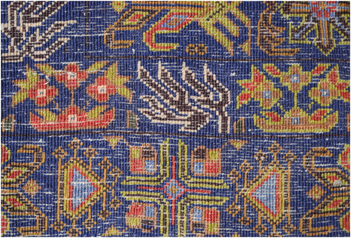 A close-up of a vintage Afghan Baluch rug featuring intricate geometric and floral patterns.