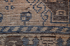 A close-up view of a vintage Afghan Baluch rug featuring a geometric pattern in brown and blue.