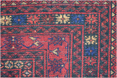 A close-up of a vintage Afghan Baluch rug featuring intricate geometric patterns in red and blue.
