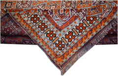 A vintage Afghan Baluch rug featuring intricate geometric patterns in orange, purple, and grey.