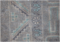 A close-up of a vintage Afghan Baluch runner featuring geometric patterns in blue and brown wool.