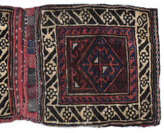 A handmade vintage Afghan wool saddle bag featuring a geometric diamond pattern in red and blue.