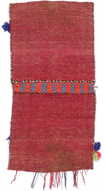 A handmade vintage Afghan wool saddle bag featuring a red field with a central geometric band.