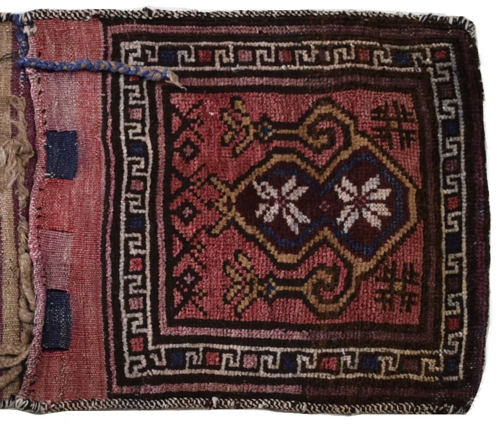 A vintage handmade Afghan wool saddle bag featuring a geometric red and brown tribal pattern.