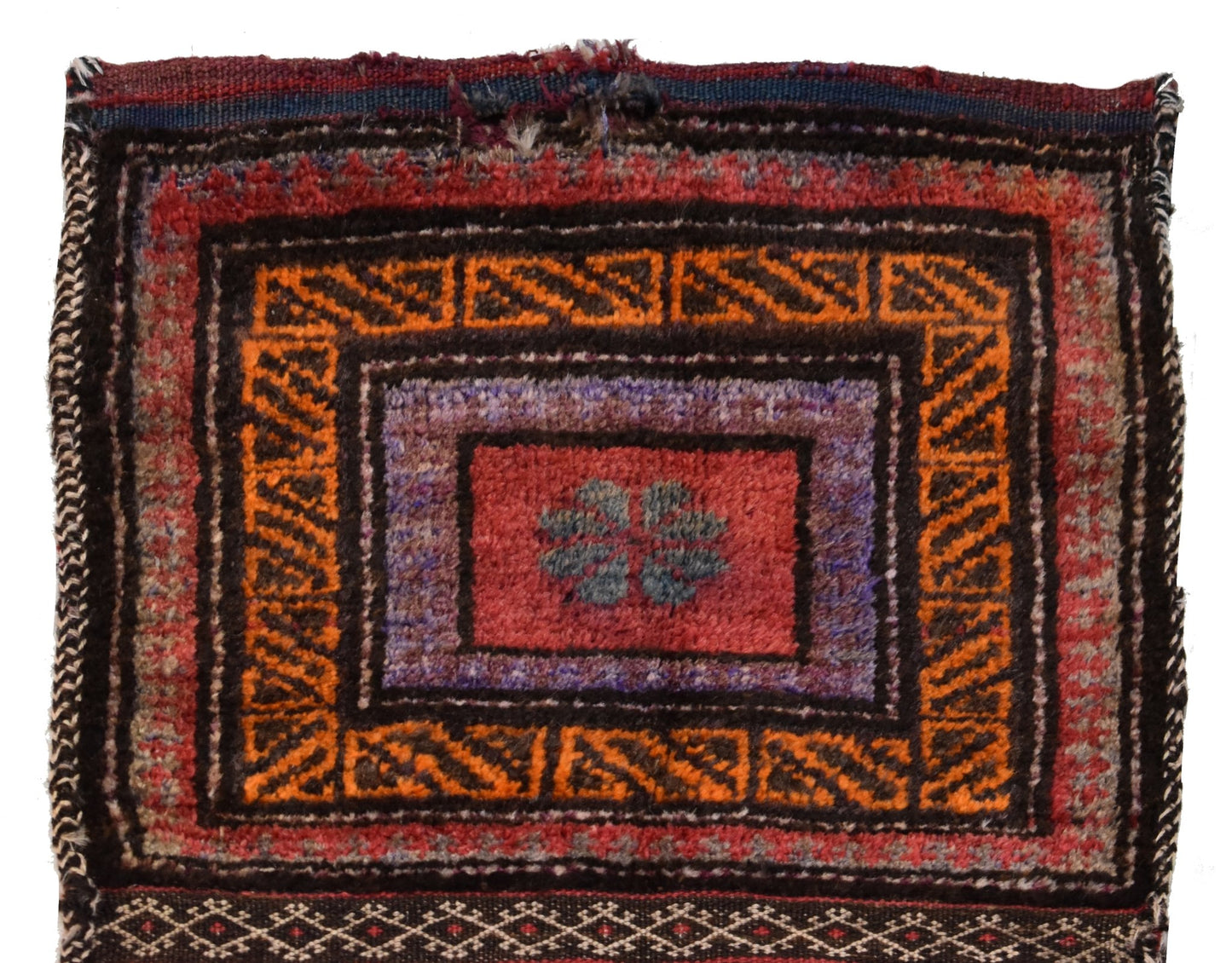 A vintage handmade Afghan wool saddle bag featuring a geometric pattern in red, orange, and purple.