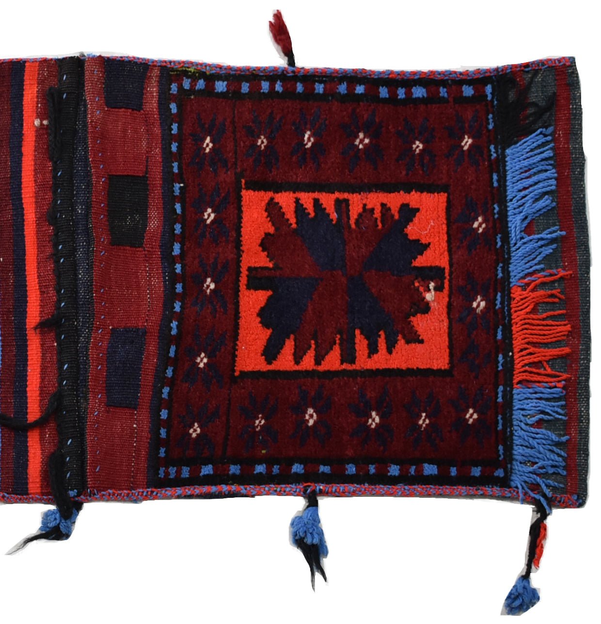 A vintage handmade Afghan wool saddle bag featuring a central geometric motif and blue fringe.
