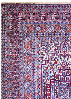 A vintage Afghan wool kilim rug featuring intricate geometric patterns in red, blue, and cream.