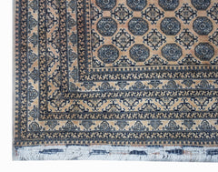 A vintage Afghan Turkmen rug featuring a geometric octagonal pattern in tan and dark blue.