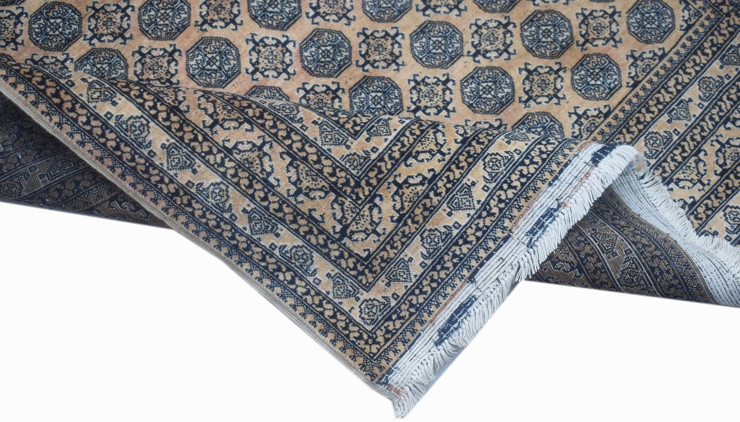 A vintage Afghan Turkmen rug featuring a geometric pattern in blue and tan with a fringed edge.