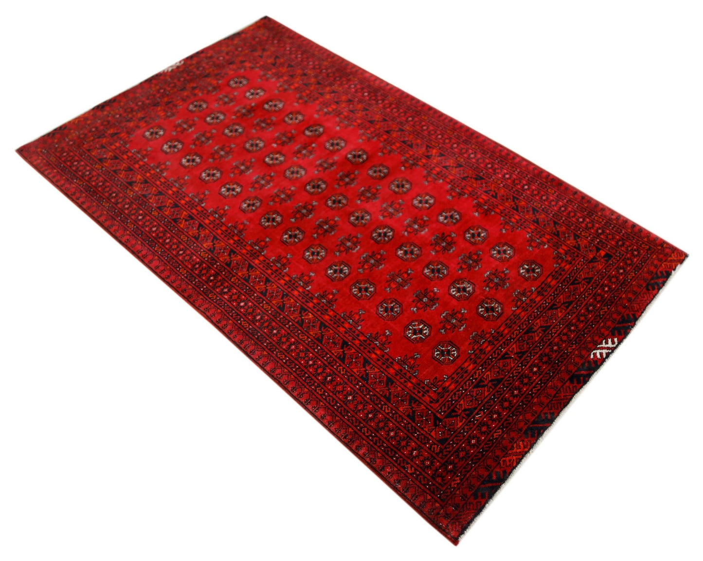 A vintage handwoven Afghan Turkmen rug featuring a repeating geometric pattern on a red field.