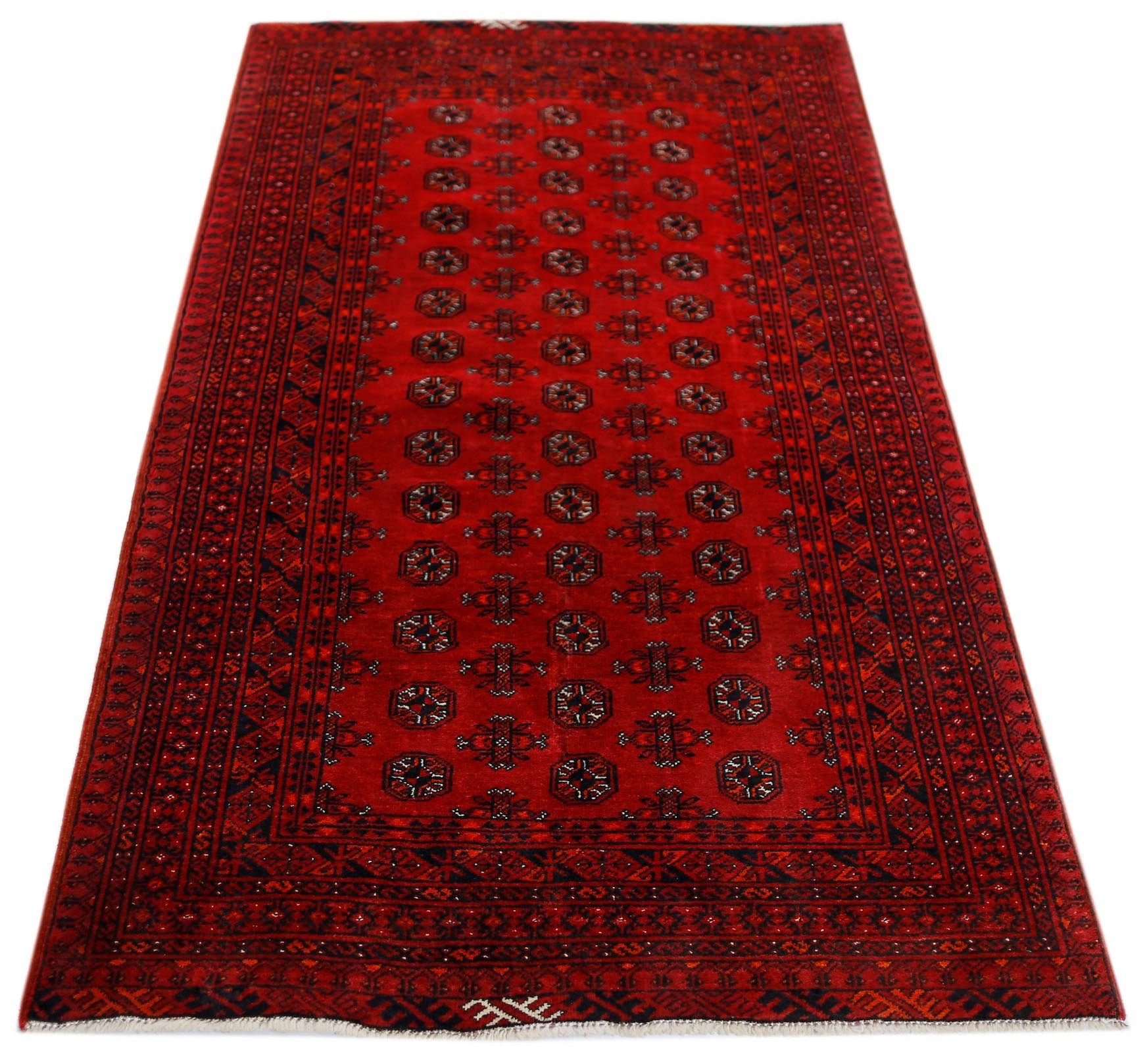 A vintage handwoven Afghan Turkmen rug featuring a repeating geometric pattern in deep red wool.