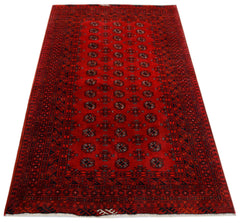 A vintage handwoven Afghan Turkmen rug featuring a repeating geometric pattern in deep red wool.