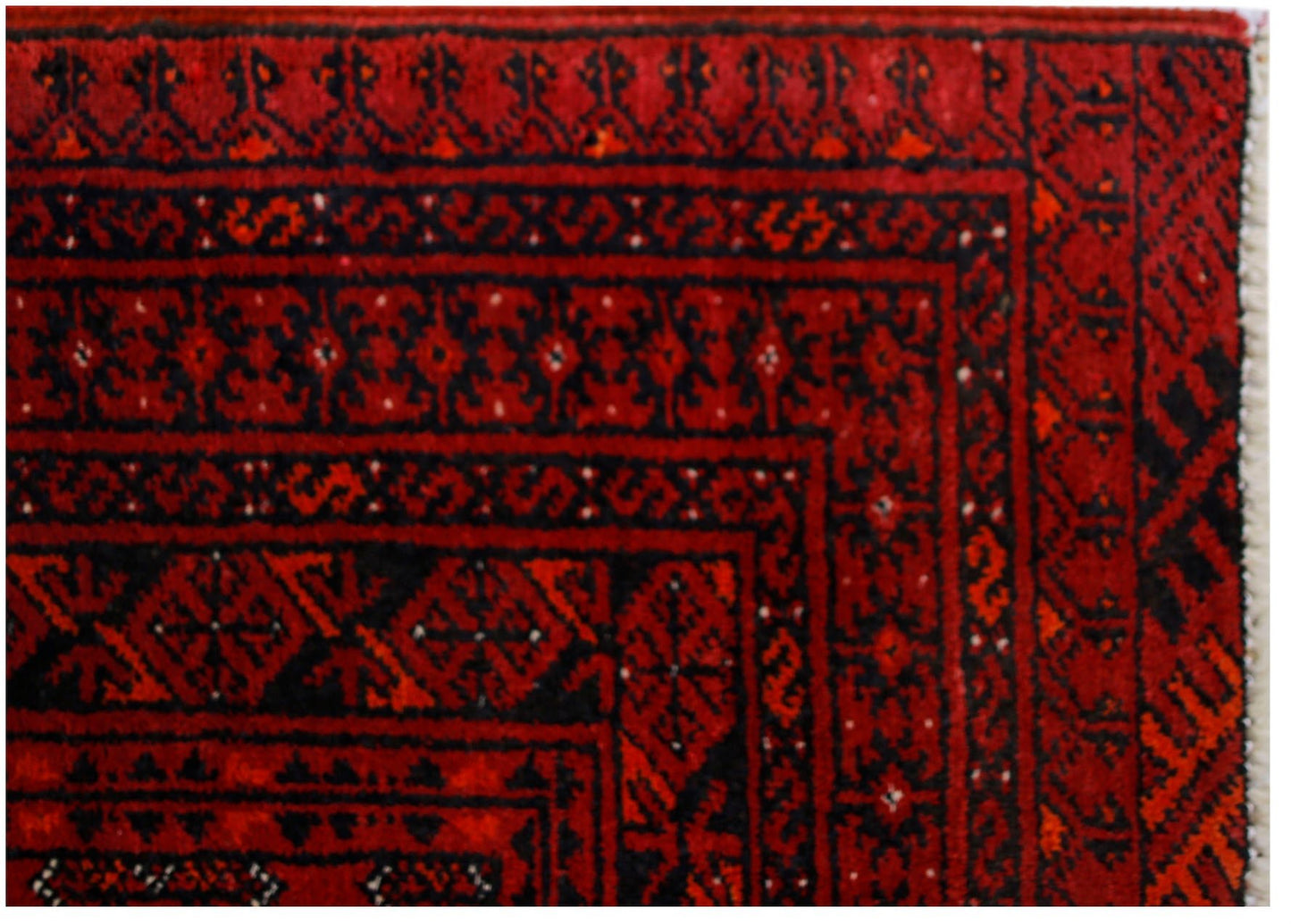 A vintage Afghan Turkmen rug featuring traditional geometric patterns in deep red and black.