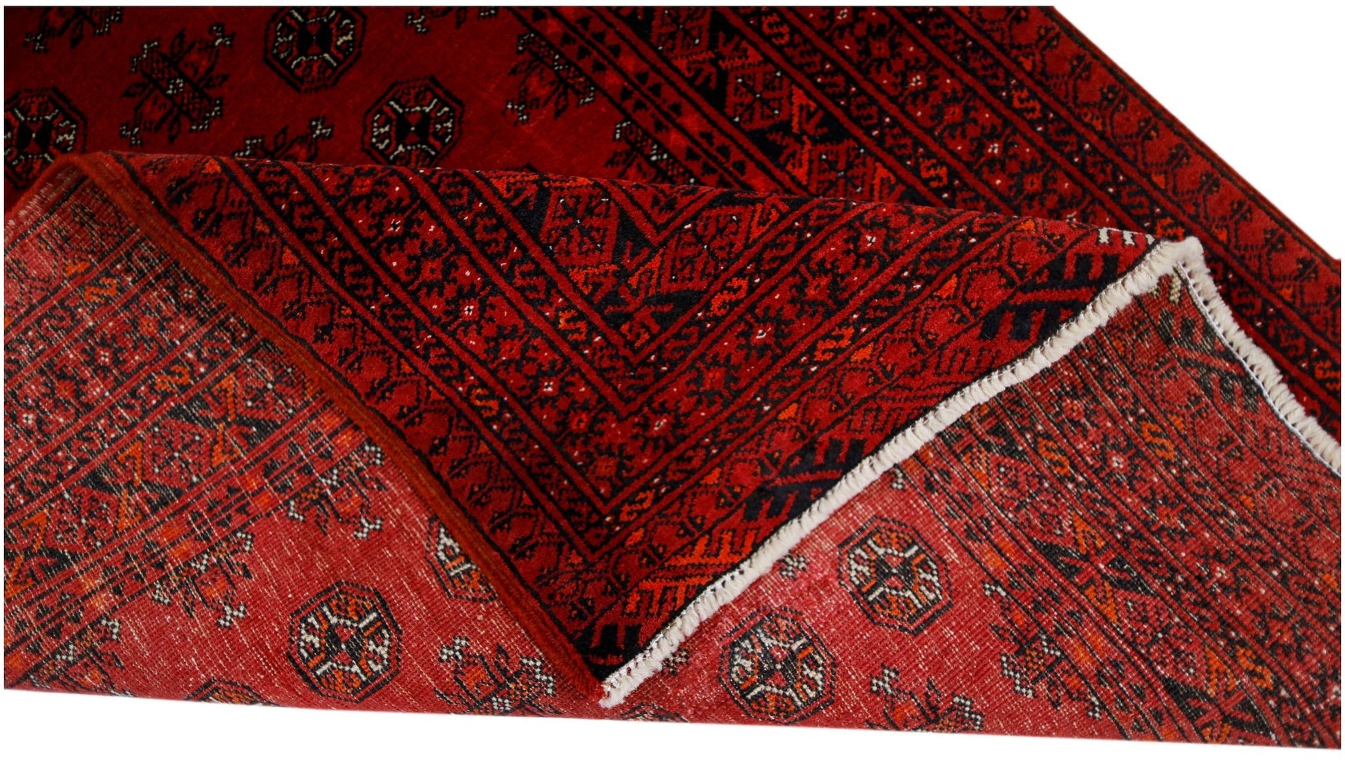 A vintage handwoven Afghan Turkmen rug featuring a red field with repeating geometric motifs.