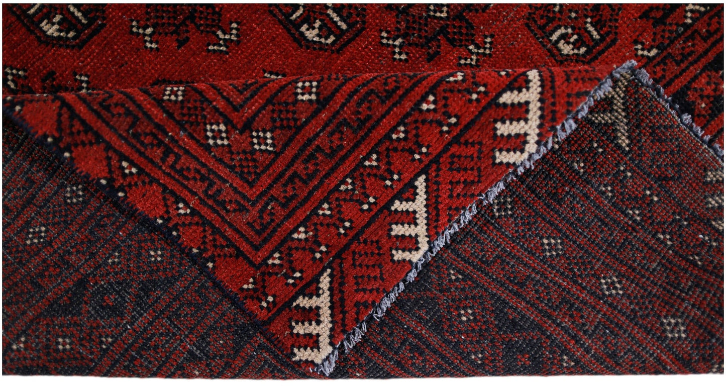 A handwoven vintage Afghan Turkmen rug featuring a geometric red and black pattern.