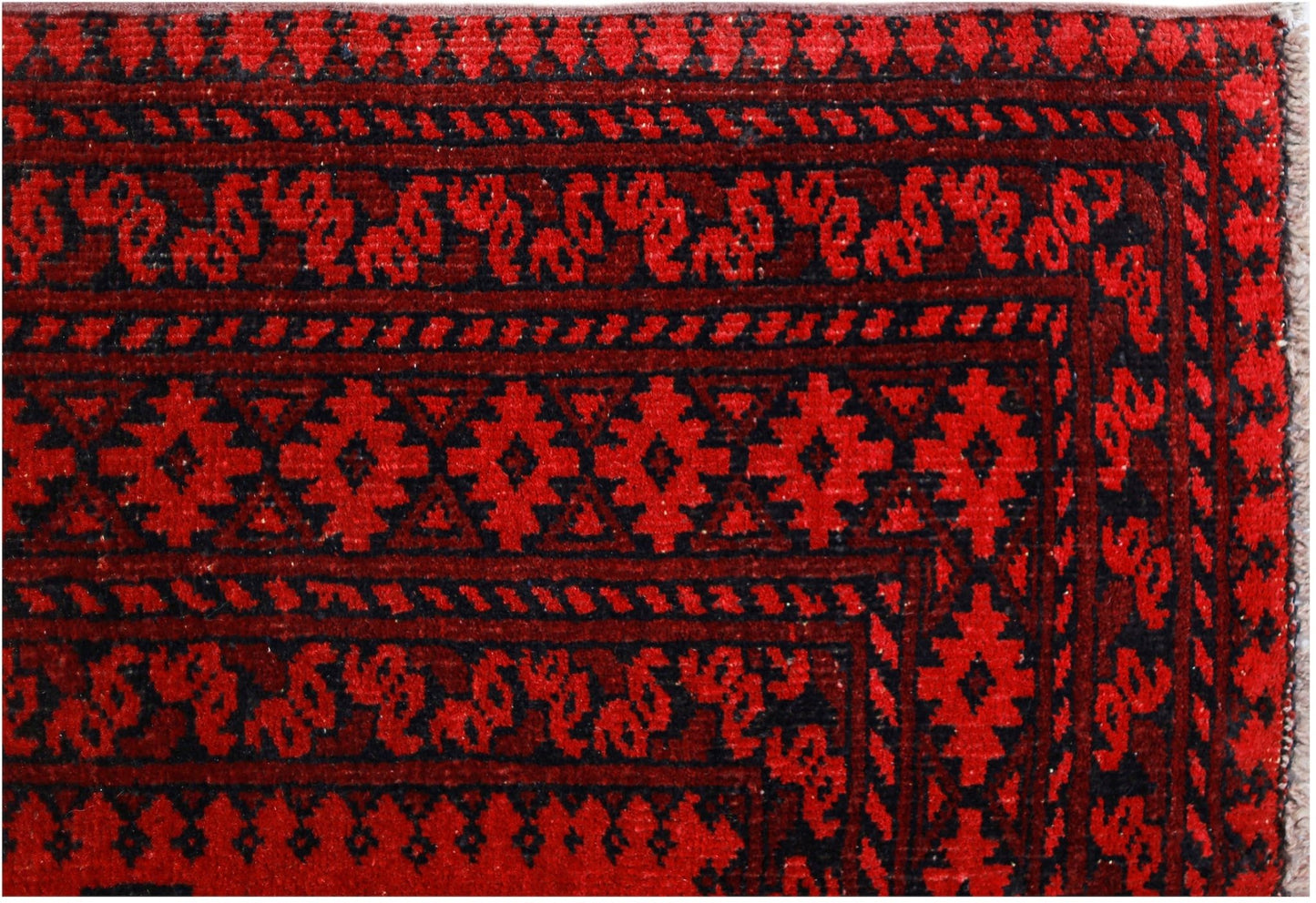 A vintage Afghan Turkmen rug featuring traditional geometric patterns in deep red and black.