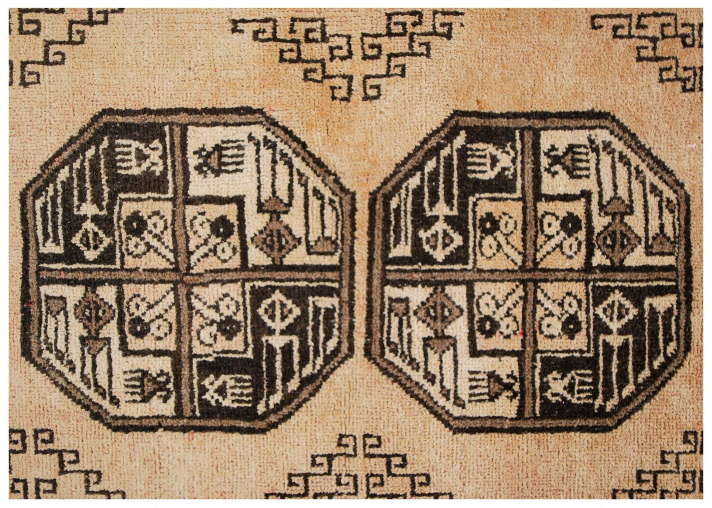 A vintage Afghan Turkmen rug featuring geometric octagonal motifs in dark brown on a natural wool background.