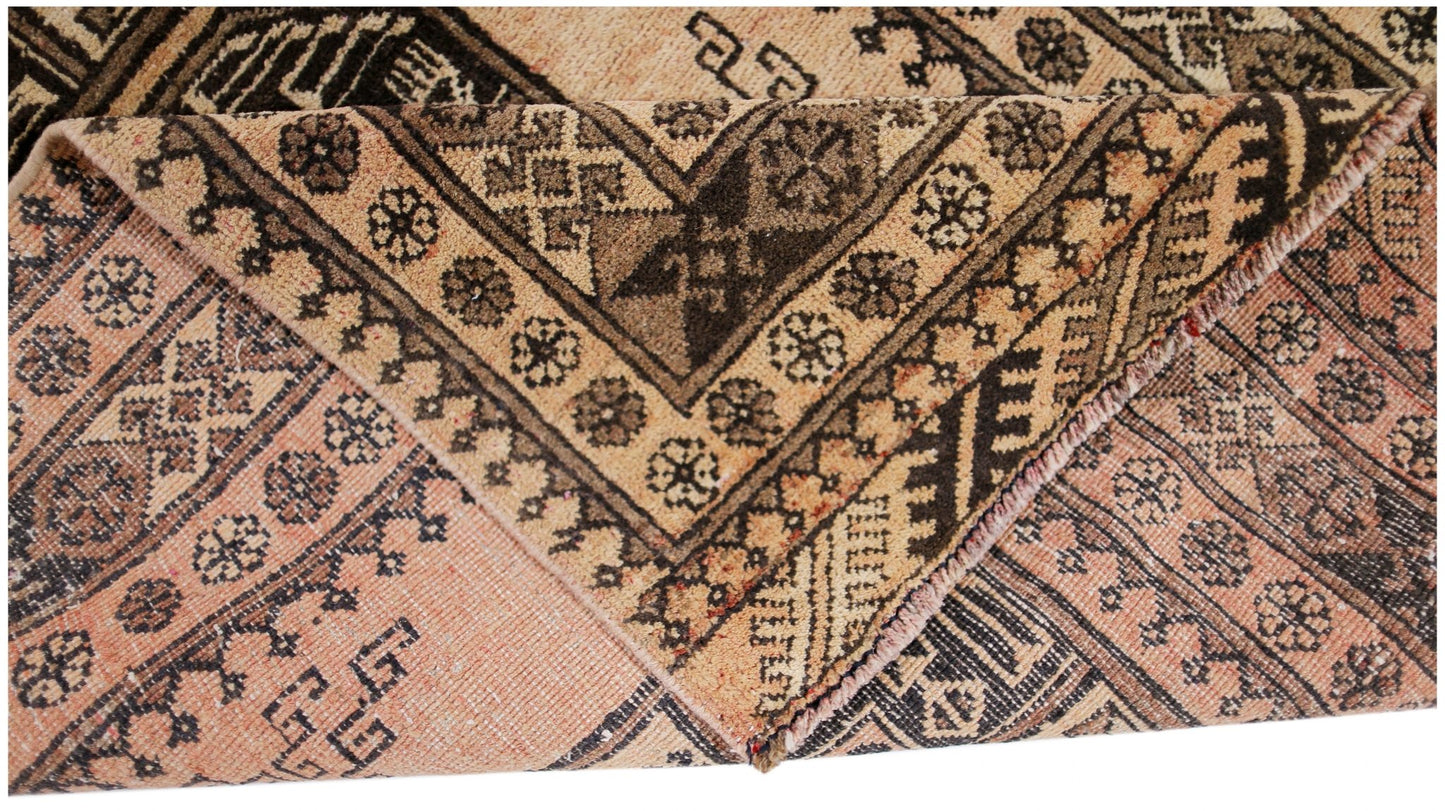 A vintage Afghan Turkmen rug with a folded corner showing intricate geometric patterns in wool.