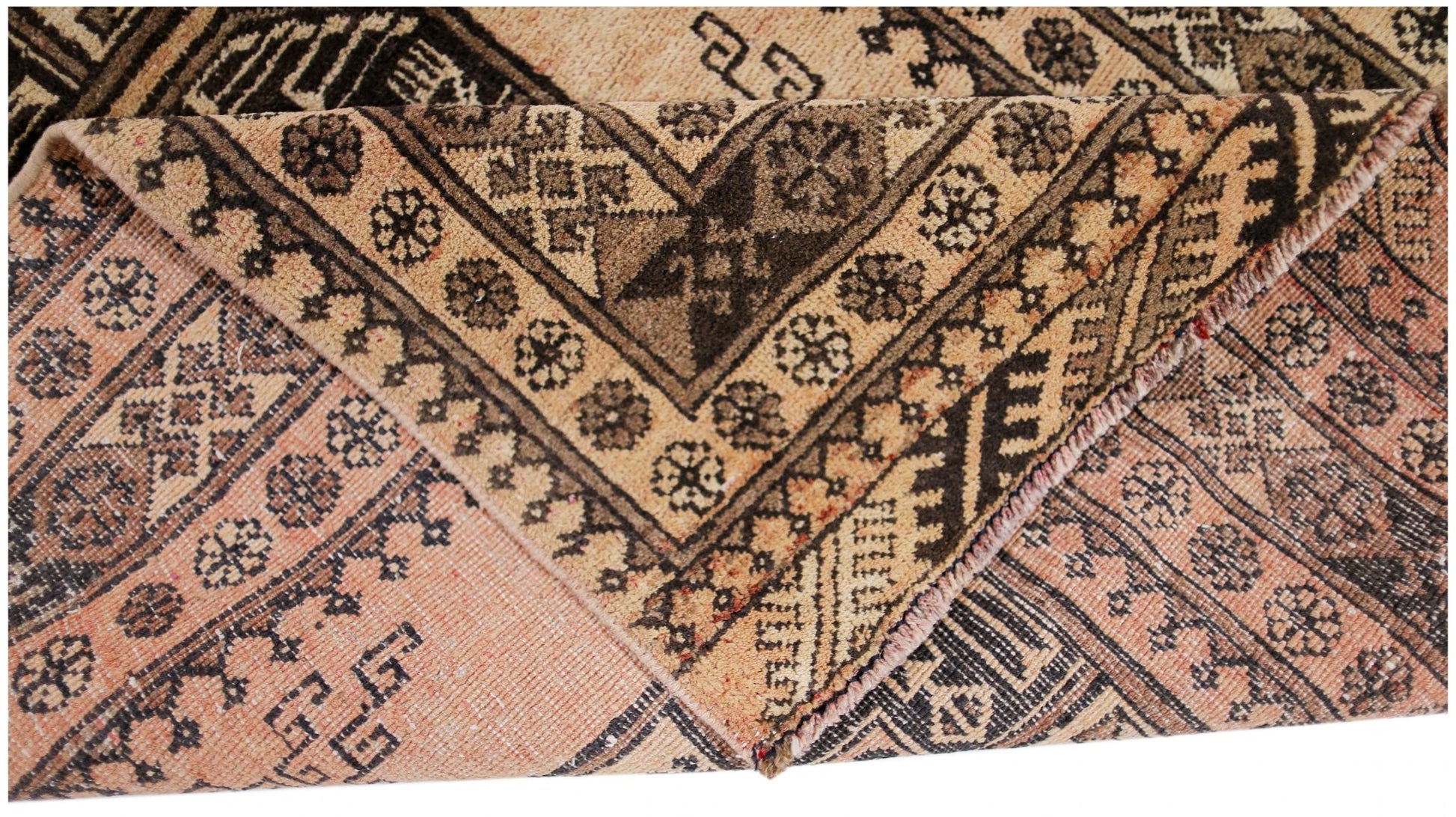 A vintage Afghan Turkmen rug with a folded corner showing intricate geometric patterns in wool.