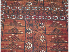 A vintage handwoven Afghan Turkmen rug featuring geometric patterns in shades of red and black.
