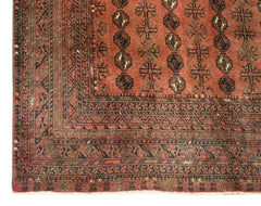 A vintage Afghan Turkmen rug featuring geometric elephant foot motifs in shades of red and black.