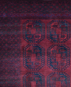 A vintage Afghan Turkmen rug featuring repeating dark blue geometric octagons on a deep red field.
