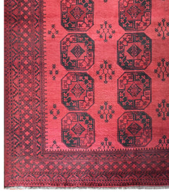 A vintage handmade Afghan Turkmen rug featuring repeating dark octagonal motifs on a red field.