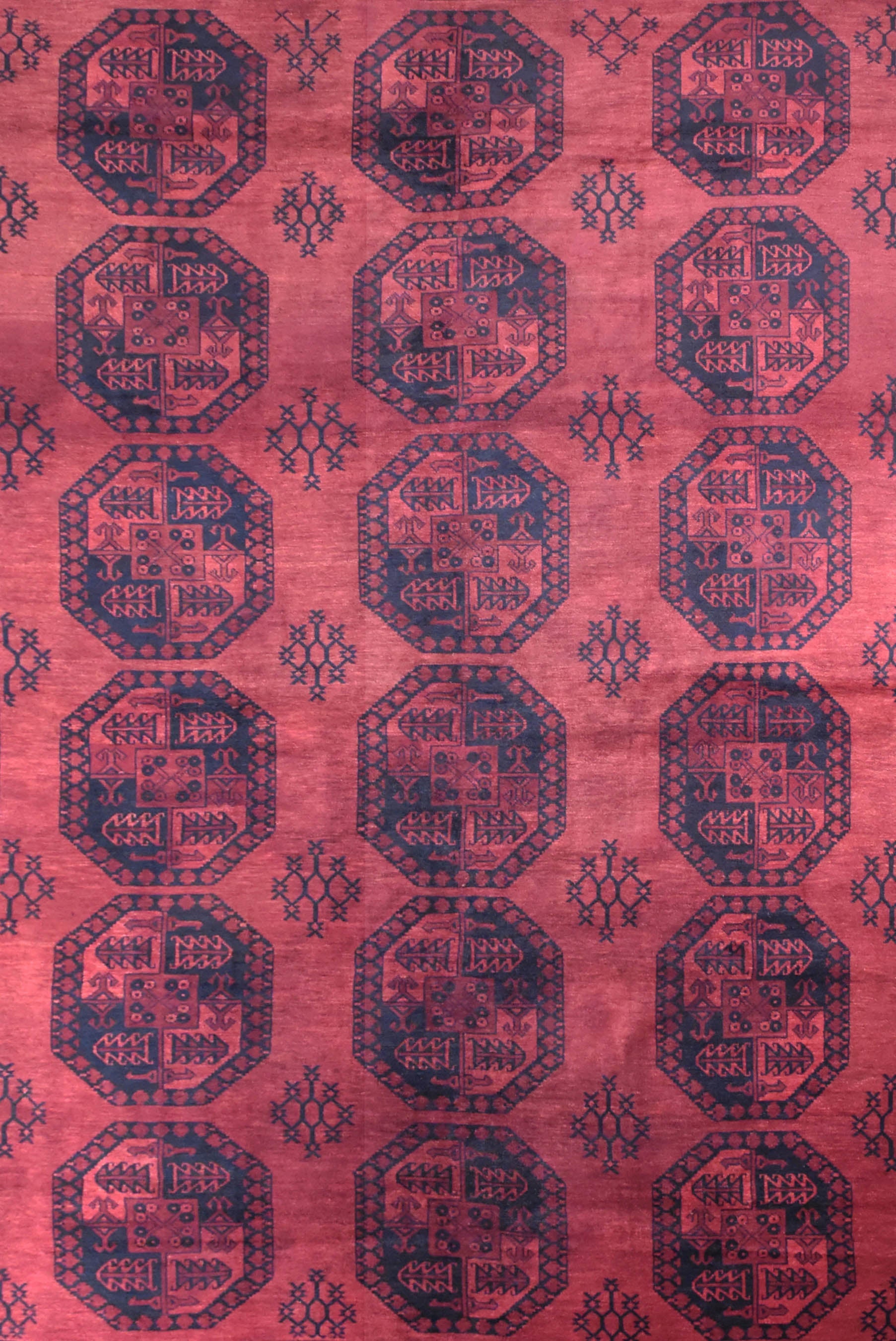 A vintage handmade Afghan Turkmen rug featuring a repeating geometric octagonal pattern in red.